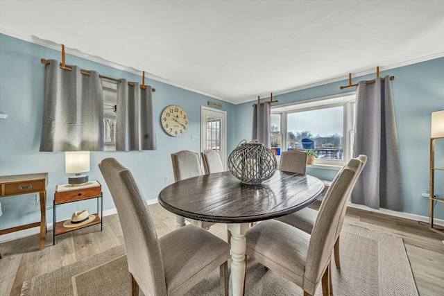 dining space with light hardwood / wood-style flooring and ornamental molding