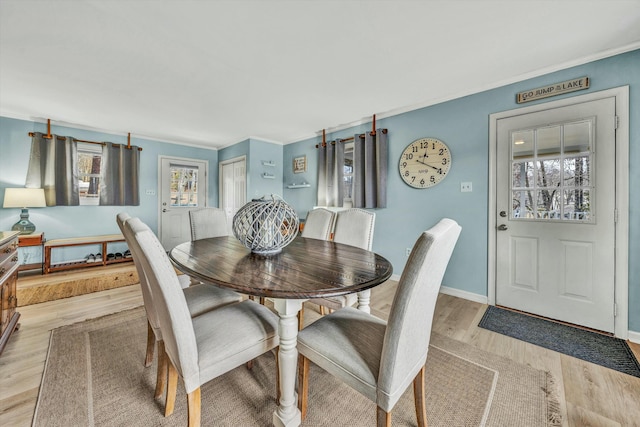 dining space with crown molding and light wood-type flooring