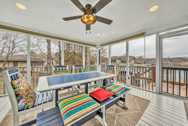 sunroom featuring a water view and ceiling fan