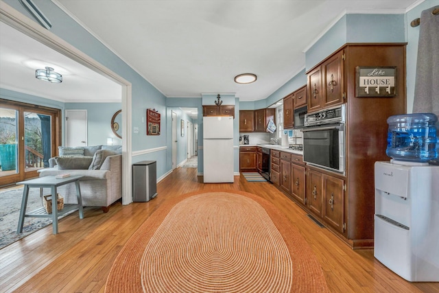 kitchen featuring plenty of natural light, wall oven, white fridge, and light hardwood / wood-style flooring