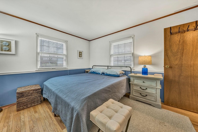 bedroom with multiple windows, ornamental molding, and light hardwood / wood-style flooring