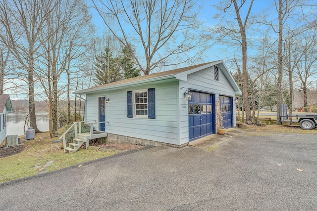 exterior space with cooling unit, a water view, a garage, and an outdoor structure