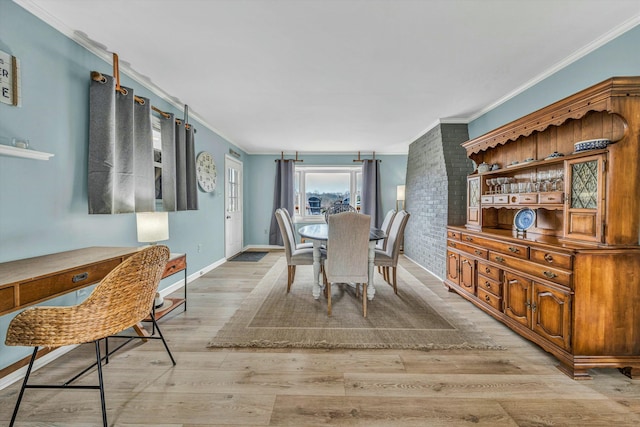 dining space with crown molding and light wood-type flooring