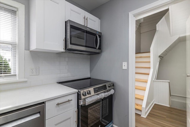 kitchen featuring white cabinetry, backsplash, light hardwood / wood-style flooring, and stainless steel appliances