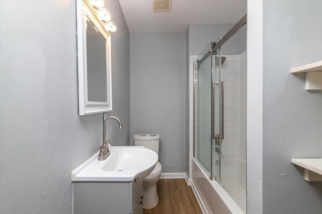 full bathroom with bath / shower combo with glass door, vanity, toilet, and hardwood / wood-style flooring