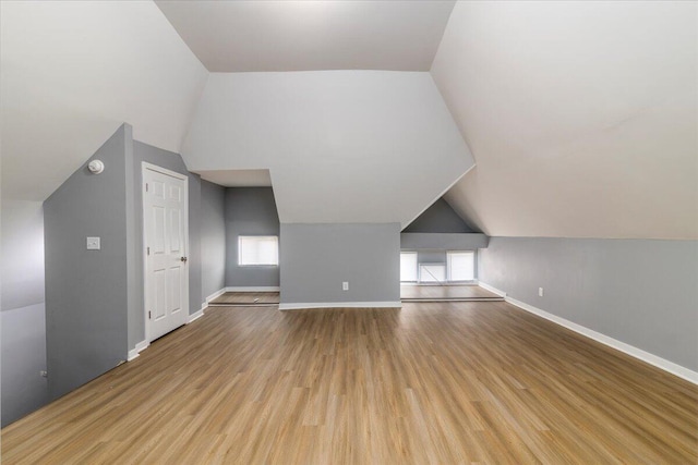 additional living space with lofted ceiling, light hardwood / wood-style flooring, and plenty of natural light