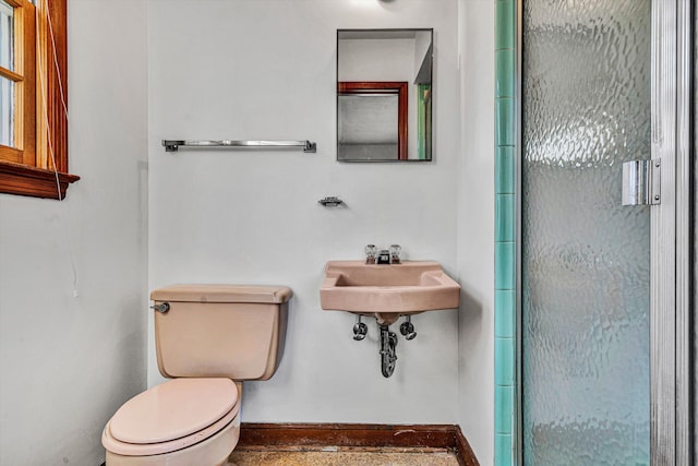 bathroom with a shower with shower door and toilet