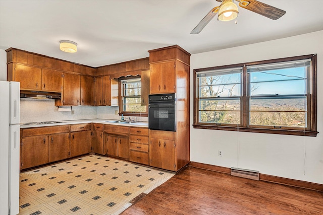 kitchen with tasteful backsplash, oven, white refrigerator, gas cooktop, and light hardwood / wood-style flooring