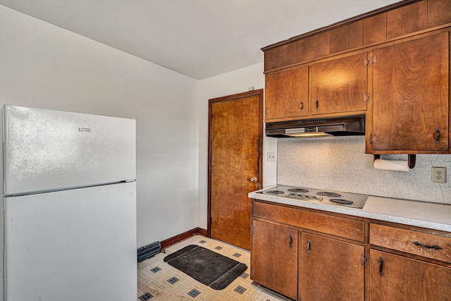 kitchen featuring white refrigerator, cooktop, and decorative backsplash