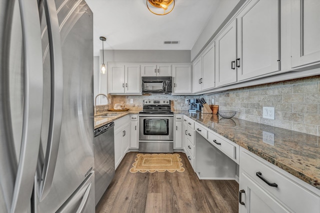 kitchen with white cabinetry, appliances with stainless steel finishes, stone countertops, and sink