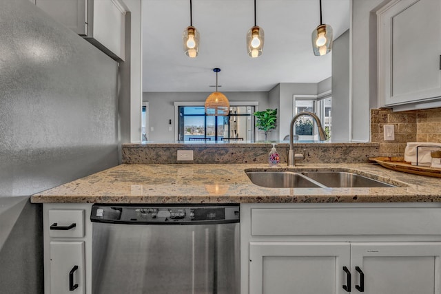 kitchen featuring pendant lighting, light stone countertops, white cabinetry, and stainless steel dishwasher