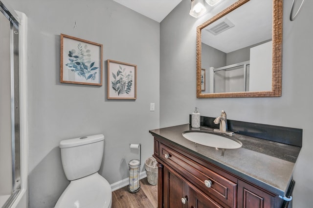 bathroom with an enclosed shower, hardwood / wood-style floors, vanity, and toilet