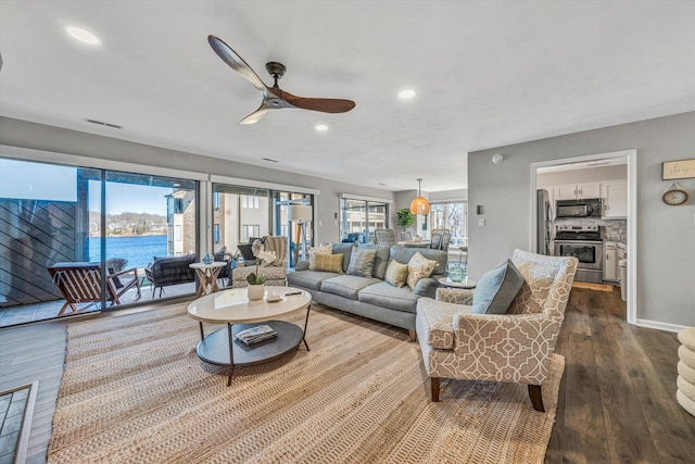 living room featuring a water view, a healthy amount of sunlight, wood-type flooring, and ceiling fan