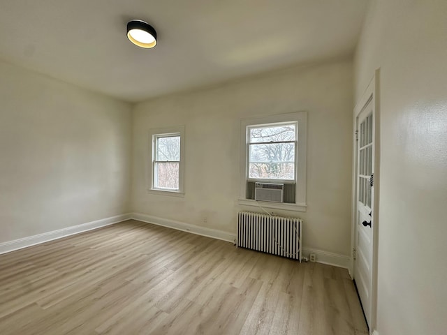 empty room with wood finished floors, radiator heating unit, cooling unit, and baseboards