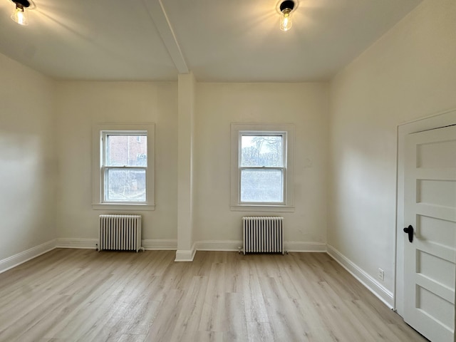 spare room featuring radiator heating unit, wood finished floors, and a wealth of natural light