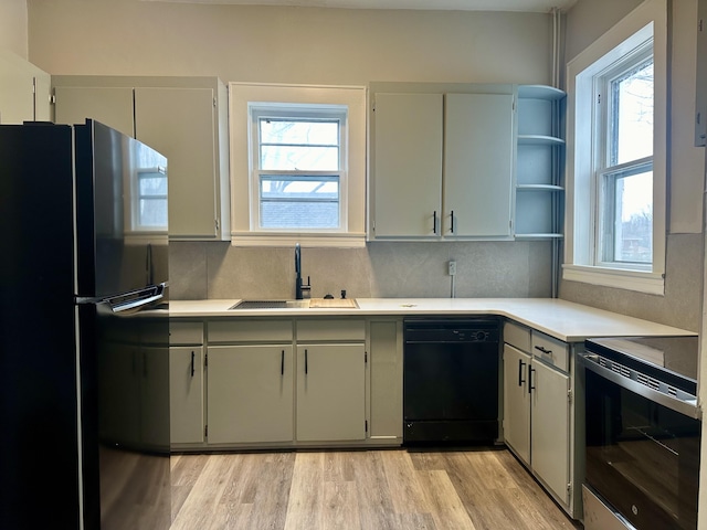 kitchen with a wealth of natural light, light countertops, a sink, and black appliances