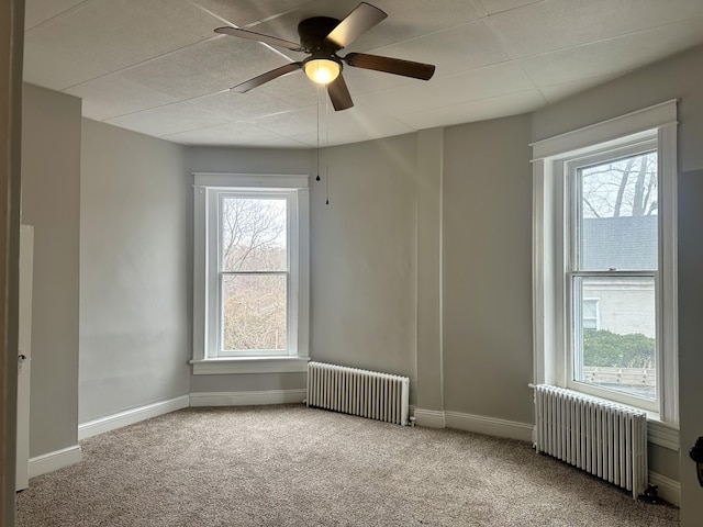 carpeted spare room with radiator heating unit and a healthy amount of sunlight