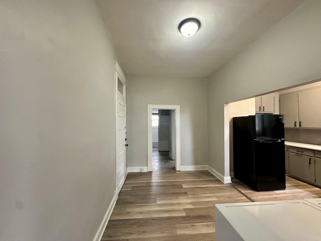 kitchen featuring light wood-type flooring, baseboards, light countertops, and freestanding refrigerator