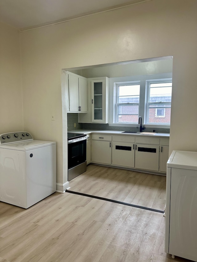 clothes washing area with washer / dryer, laundry area, light wood finished floors, and a sink