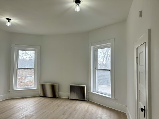 empty room featuring wood finished floors, a wealth of natural light, and radiator