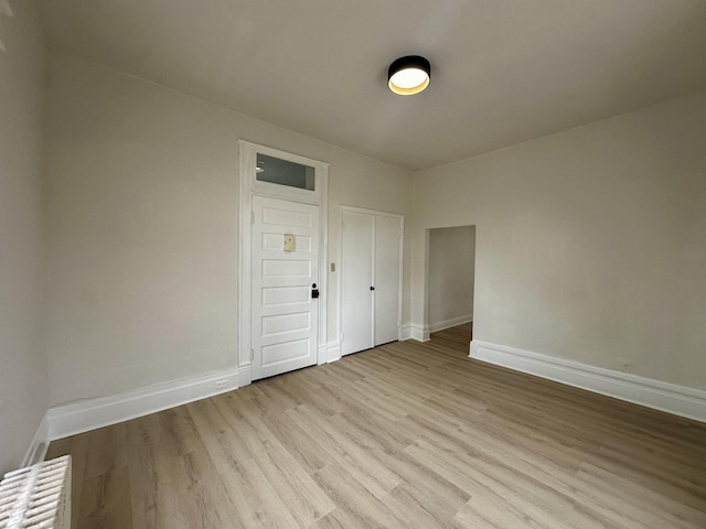 spare room with light wood-type flooring, baseboards, and radiator heating unit