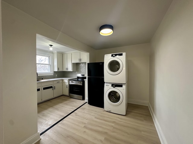 laundry area featuring a sink, light wood-style floors, baseboards, and stacked washer / dryer