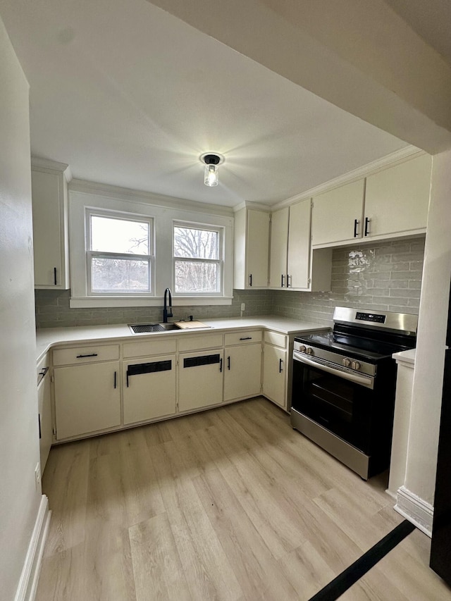 kitchen featuring crown molding, light countertops, electric range, decorative backsplash, and a sink