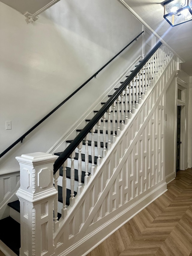 stairway featuring wainscoting and a decorative wall