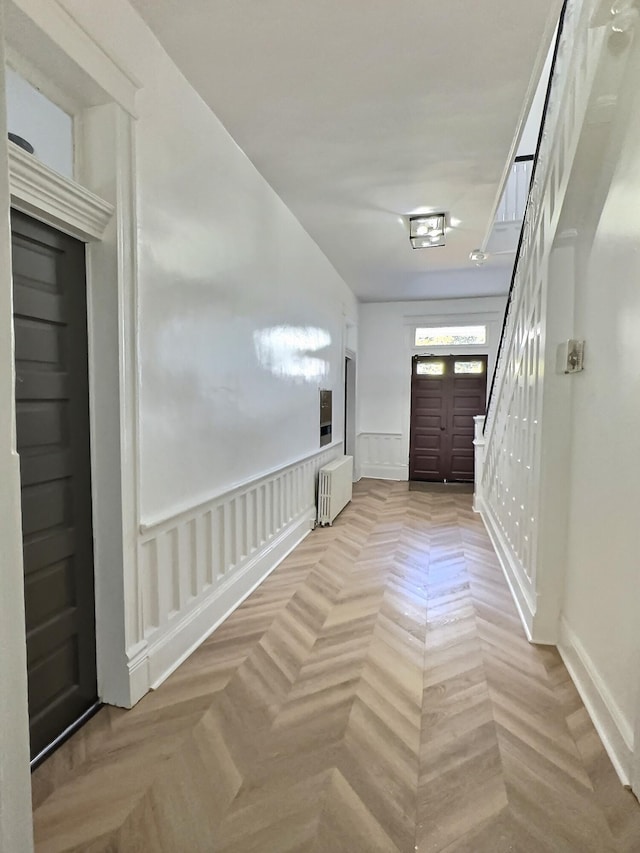 hallway featuring a wainscoted wall, a decorative wall, and radiator