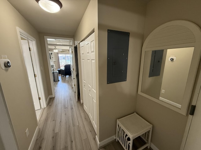 hall featuring light wood-style floors, electric panel, and baseboards