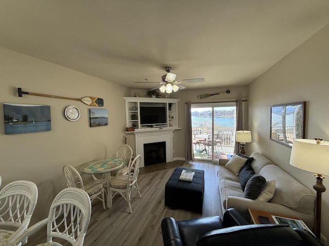 living room featuring a fireplace, wood finished floors, a ceiling fan, and baseboards