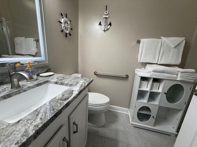 bathroom featuring toilet, marble finish floor, vanity, and baseboards