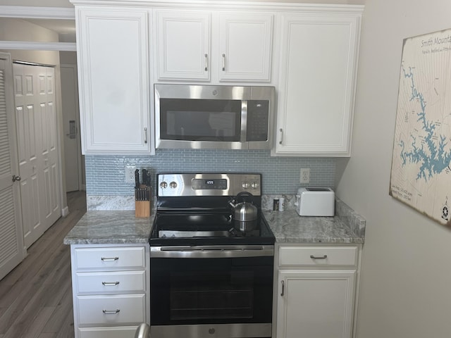 kitchen with light stone counters, tasteful backsplash, appliances with stainless steel finishes, white cabinetry, and wood finished floors