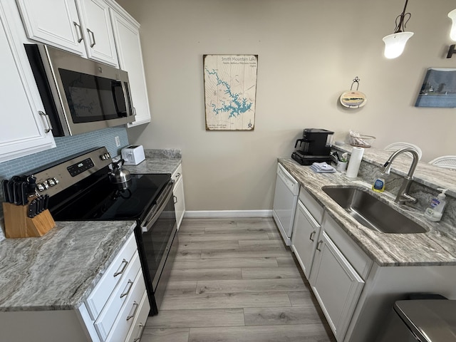 kitchen with tasteful backsplash, appliances with stainless steel finishes, a peninsula, light wood-style floors, and a sink