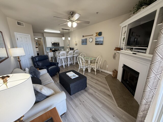 living room with light hardwood / wood-style flooring and ceiling fan