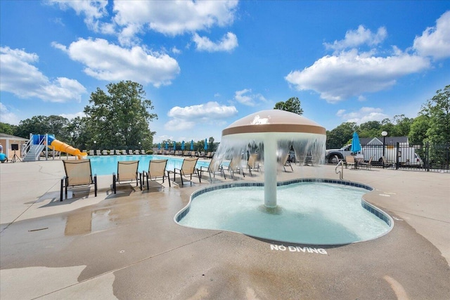 pool with a patio, a water slide, playground community, and fence