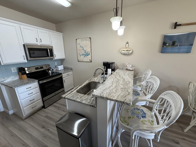 kitchen featuring sink, white cabinetry, decorative light fixtures, white appliances, and light hardwood / wood-style floors