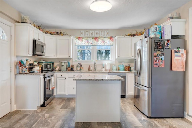 kitchen featuring sink, white cabinetry, light stone counters, appliances with stainless steel finishes, and a kitchen island