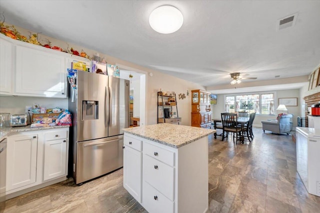 kitchen featuring white cabinetry, stainless steel fridge, light stone countertops, and a kitchen island