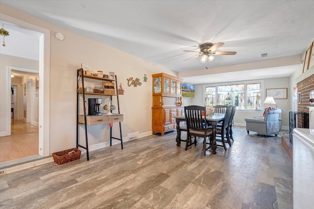 dining area with a brick fireplace and ceiling fan