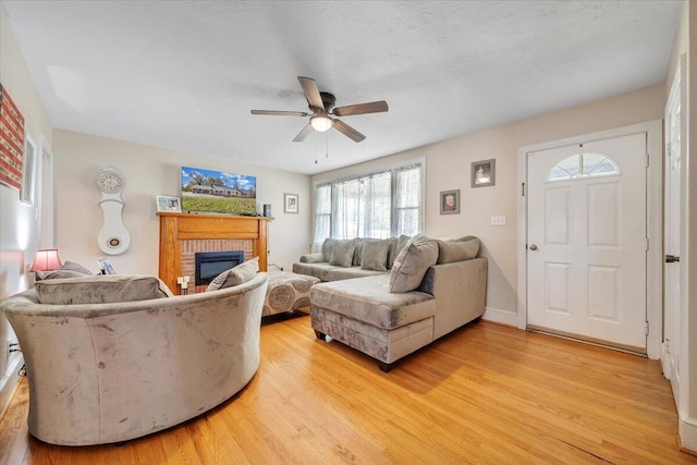 living room featuring a brick fireplace, light hardwood / wood-style floors, and ceiling fan