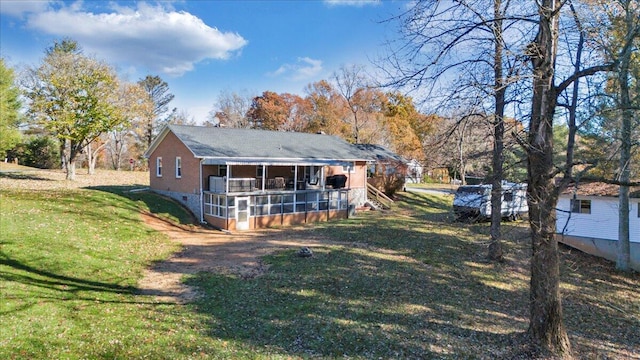 rear view of house with a lawn and a sunroom