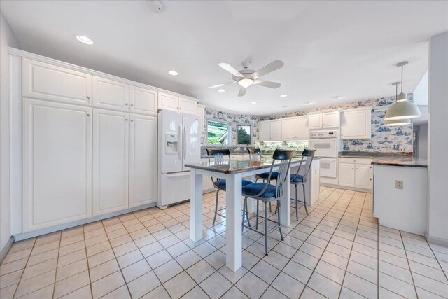 kitchen featuring pendant lighting, light tile patterned floors, white appliances, and white cabinets