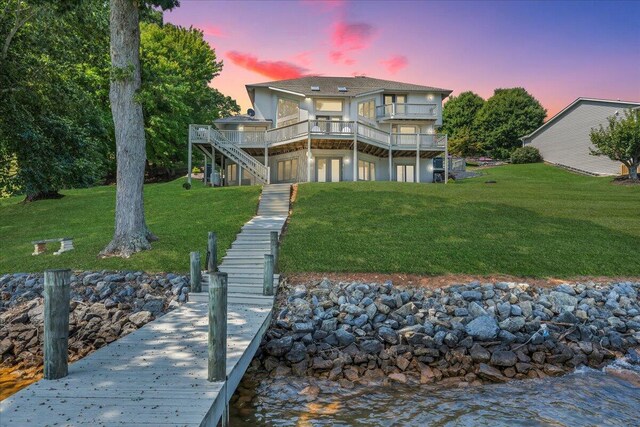 back house at dusk featuring a yard and a deck