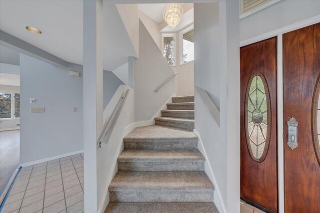 stairs featuring an inviting chandelier, tile patterned floors, and a wealth of natural light