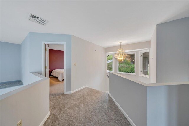 hall featuring light colored carpet and a chandelier