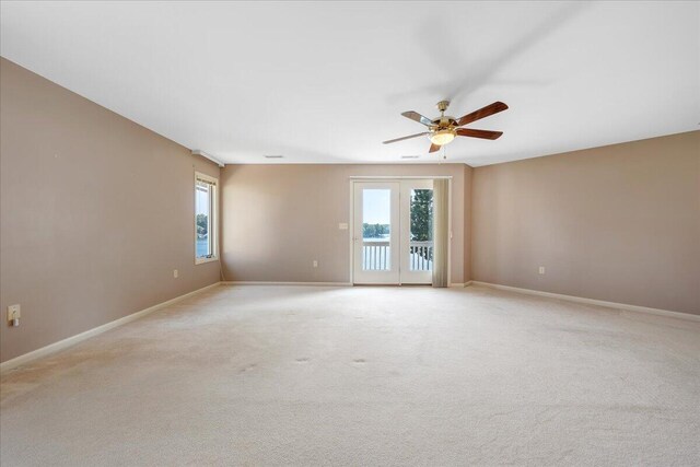 unfurnished room with light colored carpet, french doors, and ceiling fan