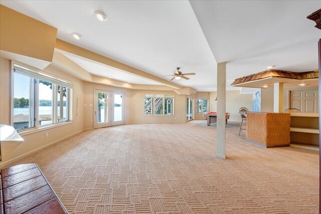 interior space with a water view, light colored carpet, and ceiling fan