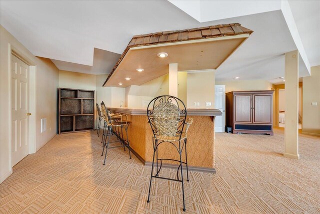 kitchen featuring light colored carpet, a kitchen bar, and kitchen peninsula