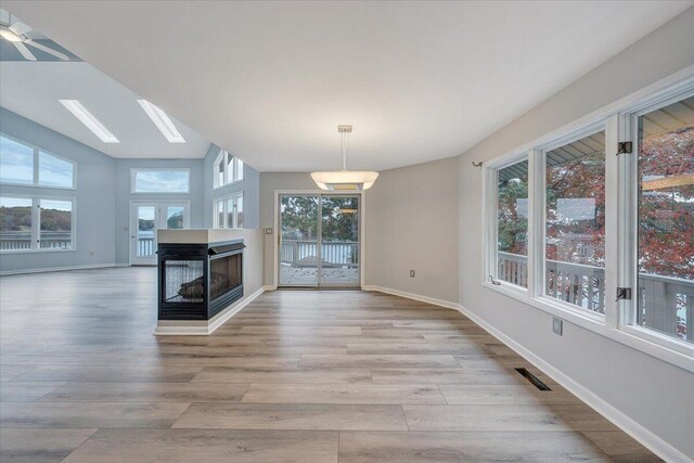 interior space featuring a skylight, light hardwood / wood-style flooring, plenty of natural light, and a multi sided fireplace